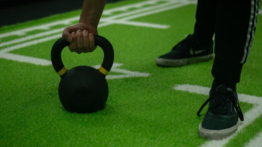 Czarny kettlebell na zielonej trawie w O Knapik Studio. Ćwiczenia z obciążeniem.